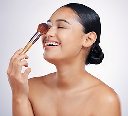 Image showing Face, makeup brush and beauty of a woman in studio for skin glow, dermatology and cosmetics. Happy female model laugh with cosmetic tools in hand for self care and facial shine on a white background