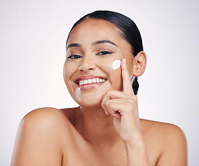 Image showing Woman in portrait, lotion on face and beauty with skincare, smile and moisturizer isolated on studio background. Happy female model apply cream, dermatology and cosmetic product with skin glow