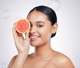 Image showing Face, grapefruit and beauty portrait of a woman in studio for glow and natural dermatology. Female person with a fruit in hand and bubbles for facial detox, vitamin c and health on a white background