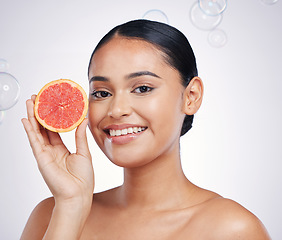 Image showing Face, grapefruit and beauty portrait of woman in studio for skin glow, dermatology or natural cosmetics. Model person with fruit and bubbles for detox, healthy diet and skincare on a white background