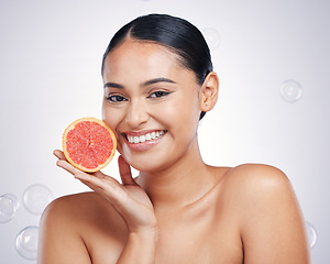 Image showing Face, grapefruit and beauty portrait of a woman in studio for skin glow, dermatology or natural cosmetic. Happy person with fruit and bubbles for detox, healthy diet or skincare on a white background