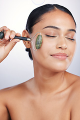 Image showing Calm woman, skincare and roller in relax for beauty or cosmetics against a white studio background. Happy female person or model rolling skin with jade stone for healthy wellness or facial treatment