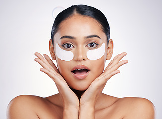 Image showing Face, eye mask and a woman in studio for beauty glow, dermatology or natural cosmetics. Portrait of surprised person with skincare patch for facial self care with wow results on a white background