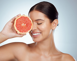 Image showing Face smile, skincare and woman with grapefruit in studio isolated on a white background. Vegan, natural and female model with fruit for vitamin c, nutrition or healthy diet, wellness or cosmetics.