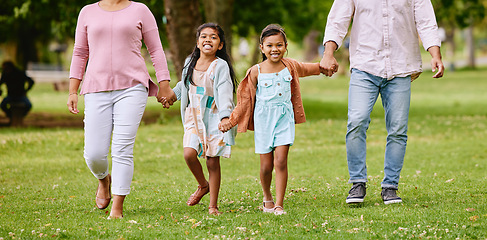 Image showing Family, park and children holding hands with parents walking, bonding and time in nature together with smile. Mother, father and kids walk on grass field for fun outdoor adventure in garden or woods