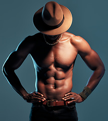 Image showing Black man, topless and strong with sexy fashion model, cow boy style with hat isolated on blue background. Dark, shadow and body with muscular male person, pose with six pack and stylish in studio