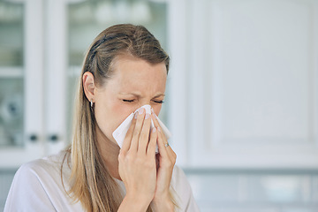 Image showing Sick, tissue and woman blowing her nose in the kitchen for a cold, flu or sneeze at her home. Illness, virus and young female person sneezing with allergies, hay fever or covid in her apartment.