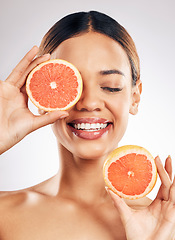 Image showing Happy, skincare and woman with grapefruit in studio for natural cosmetic, eco or beauty on grey background. Citrus, facial and female model relax with fruit for skin, detox and vitamin c or collagen