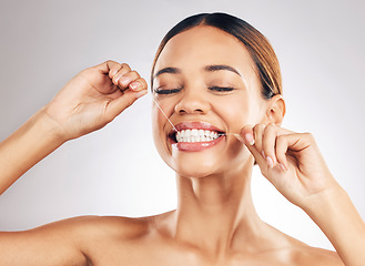 Image showing Smile, oral care and woman flossing teeth in studio for hygiene, wellness or fresh breath on grey background. Face, floss and lady relax with mouth, tooth or cleaning for dental or cavity prevention