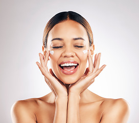 Image showing Skincare, beauty and happy woman with face cream in studio for healthy, glowing or anti aging on grey background. Facial, smile and female model excited for dermatology, results and sunscreen lotion