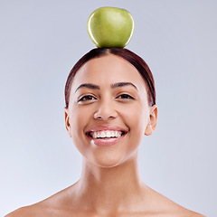 Image showing Apple, balance or portrait of happy woman in studio on white background for healthy nutrition or clean diet. Smile, face or beautiful girl with natural organic fruit on head for wellness benefits