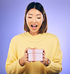 Image showing Happy, surprise and woman with a gift in a studio for birthday celebration with a wow face. Happiness, excited and Asian female model with a present, box or package isolated by a purple background.