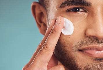 Image showing Portrait, beauty and cream with a man in studio on a gray background to apply antiaging facial treatment. Face, skincare and lotion with a young male person indoor for wellness or aesthetic self care