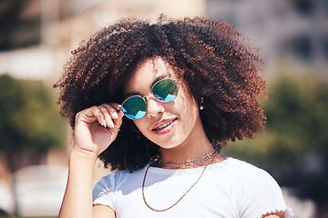 Image showing Woman, fashion and sunglasses on face outdoor in city for summer holiday and travel with a smile. Portrait of African person with natural hair or afro and trendy glasses at a park for freedom