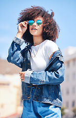 Image showing Woman, fashion and sunglasses outdoor in city for streetwear, summer and travel on a street. African person with natural hair or afro and urban background, glasses and jeans or clothes for freedom