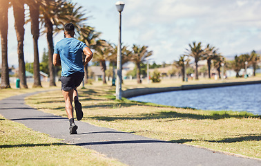 Image showing Fitness, running and a man outdoor for exercise, training or cardio health at a park. Back of male athlete on path by nature canal for morning workout, run and performance goals or healthy lifestyle