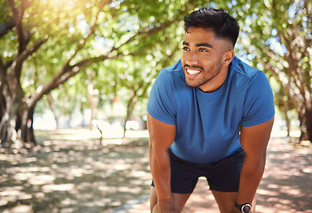 Image showing Fitness, break and man or runner outdoor for exercise, training or running at a park. Happy and tired Indian male athlete in nature for a workout, run and rest while thinking of goals or performance