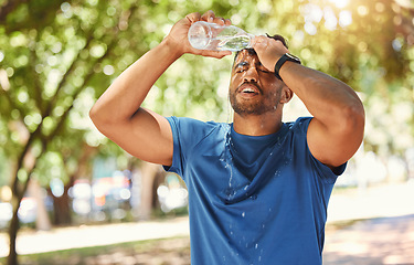 Image showing Fitness, outdoor and a man pouring water on face after exercise, training or running at a park. Tired Indian male athlete in nature for workout, run and break or cooling down with a splash in summer