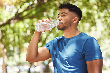 Image showing Fitness, man or runner drinking water outdoor for exercise, training or running at a park. Indian male athlete in nature for a workout, run and break to drink from a bottle for health and wellness