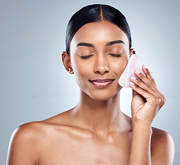 Image showing Beauty, skincare and gua sha with face of woman in studio for massage, wellness and cosmetics. Spa, self care and glow with model on grey background for facial, cosmetology and rose quartz crystal