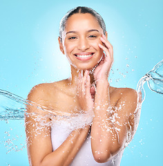 Image showing Water, splash and shower with portrait of woman in studio for hygiene, beauty and skincare. Wellness, cleaning and fresh with face of female model on blue background for spa, cosmetics and liquid