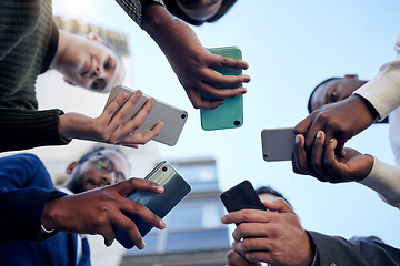 Image showing Phone, low angle and group of business people networking in city outdoor. Smartphone, circle and team network together on social media, web email or online scroll on mobile app, tech or communication