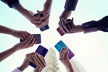 Image showing Business people, hands and circle with phone, connectivity and social media in the city. Below, sky and group with hands holding mobile in urban town with internet, web and career app with diversity