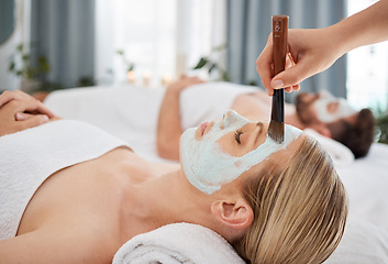 Image showing Hand, brush and mask with a couple in a spa to relax on a massage table at a luxury resort together. Wellness, skincare and face treatment with a woman customer waiting for a facial from a masseuse