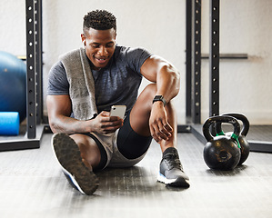 Image showing Fitness, phone and black man typing in gym on break after exercise, training or workout. Athlete, smartphone and happy African male person on sports app, networking or social media, email and relax.