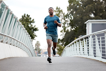 Image showing Black man, fitness and running on bridge in city for cardio exercise, workout or training outdoors. Fit, active and sporty African male person, athlete or runner exercising on a run in an urban town