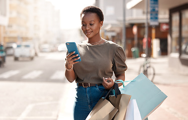 Image showing Shopping, bag and phone with black woman in city for social media, networking and communication. Fashion, retail and luxury with female customer in Nigeria Town for contact, ecommerce app and sale