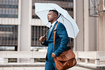 Image showing Travel, business and black man with umbrella in city for weather, rain and winter season in urban town. Corporate, professional and male entrepreneur with bag for journey, commute and travelling