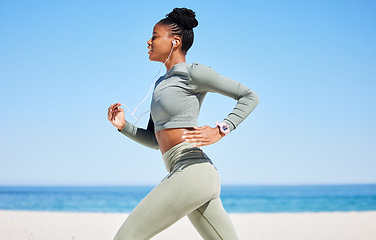 Image showing Running, beach and woman listening to music, fitness podcast and training, cardio wellness and health. Ocean, blue sky and african person, runner or athlete exercise, workout and audio technology