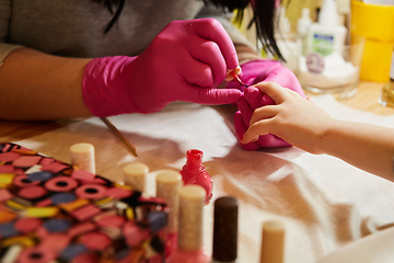 Image showing Little girl is getting manicure in beauty salon, close-up.