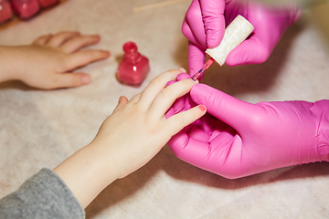 Image showing Little girl is getting manicure in beauty salon, close-up.