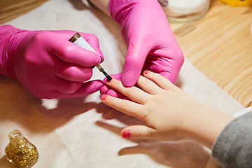 Image showing Little girl is getting manicure in beauty salon, close-up.