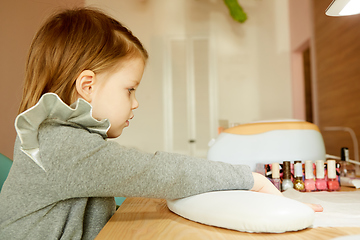 Image showing Little girl in nail salon receiving manicure by beautician. Little girl getting manicure at beauty salon.