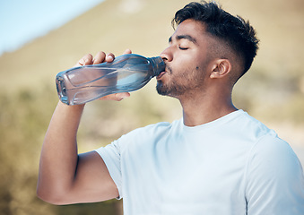 Image showing Man, fitness and drinking water in nature for sustainability, running exercise or cardio workout outdoors. Thirsty male person, athlete or runner with drink for hydration, rest or break on mountain