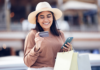 Image showing Woman, smile with credit card and smartphone, shopping bag at mall with online payment and fintech. Happy female customer at outdoor market, ecommerce with bank app and internet banking transaction