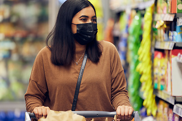 Image showing Grocery shopping, woman and cart at a retail shop, market and store for groceries with mask. Health, virus safety and female person with choice and food browse for purchase in a supermarket at shelf