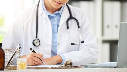 Image showing Planning, doctor writing on a clipboard and with laptop at a desk in a modern office with lens flare. Healthcare, medical research and female nurse or surgeon with stethoscope write notes at work