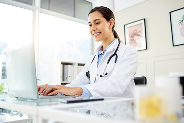 Image showing Research, woman doctor with computer and at her desk of her workplace office with a lens flare. Networking, connectivity and female surgeon on pc typing an email with a smile at her workspace