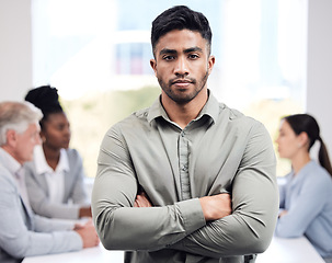 Image showing Portrait, serious and a business man arms crossed in the boardroom with his team planning in the background. Leadership, workshop and focus with a confident young male employee standing in the office