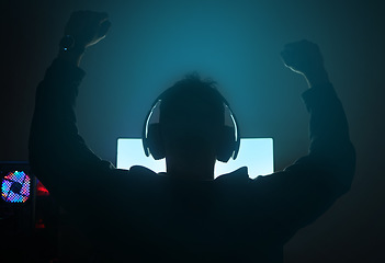 Image showing Man in dark room, silhouette with video game and winning, fist pump and online streaming with gaming competition. Esports, cyber and male streamer back, celebrate win for gamer tournament and success