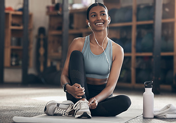 Image showing Woman in gym, relax with earphones and fitness, workout and listening to music with smile and sports. Healthy, active with happy Indian female sitting in exercise studio and music for motivation