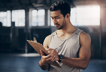 Image showing Sports, clipboard and male personal trainer in the gym working on a training schedule checklist. Young, confident and man athlete coach writing workout or exercise plan for wellness in fitness center