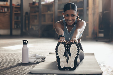 Image showing Woman is stretching legs in gym, fitness and smile, start workout with earphones, portrait and sport preparation. Health, active with happy Indian female warm up and ready for exercise with music