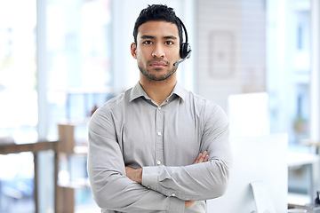 Image showing Call center, man and portrait with arms crossed in office, telemarketing or serious face for crm job. Young indian consultant, voip headset and customer service for advice, sales or technical support