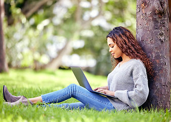 Image showing Woman, student and typing on laptop at a park outdoor for education, research or studying. African person at university or college campus tree in nature with tech for knowledge, internet and learning