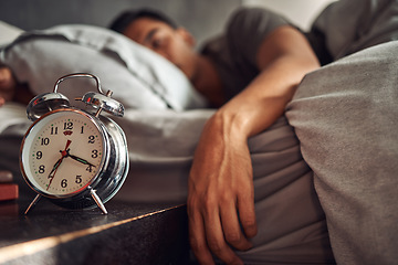 Image showing Alarm clock, relax and man sleeping in the bed of his modern apartment in the morning. Lazy, resting and closeup of a timer bell with a male person taking a nap and dreaming in bedroom at his home.